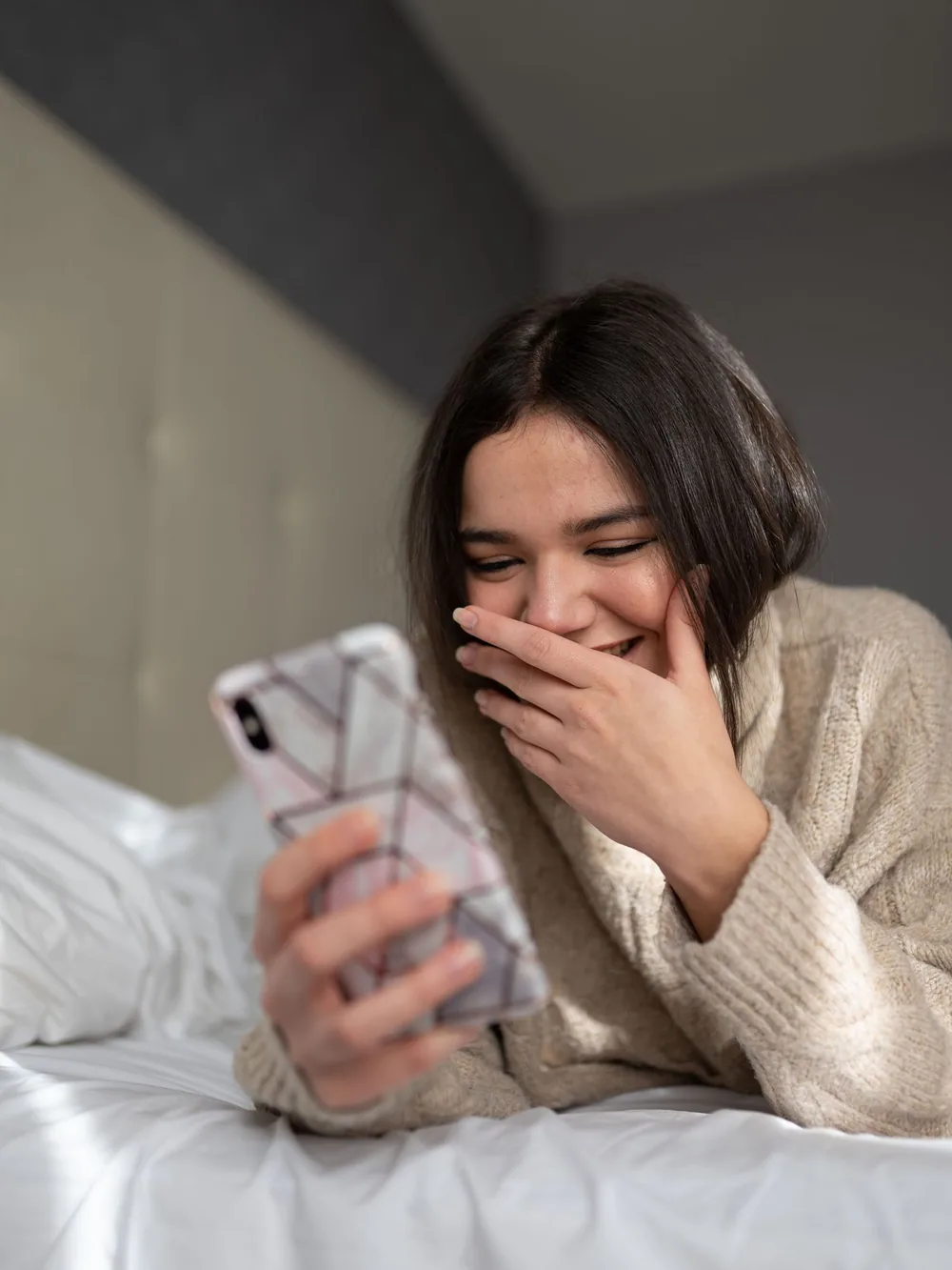 Kobieta uśmiechająca się do wiadomości na telefonie